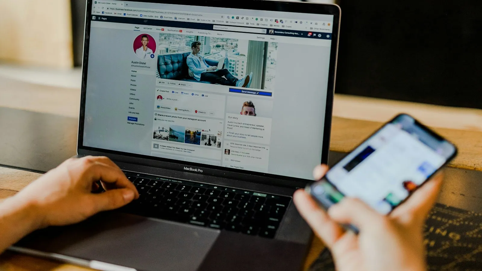 A person manages a social media page on a laptop while holding a phone.
